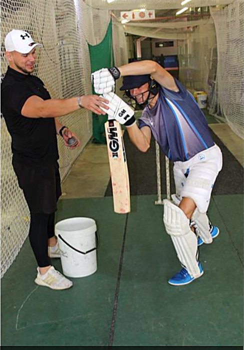 Coach Jared Newton adjusting a young batter's grip in the nets